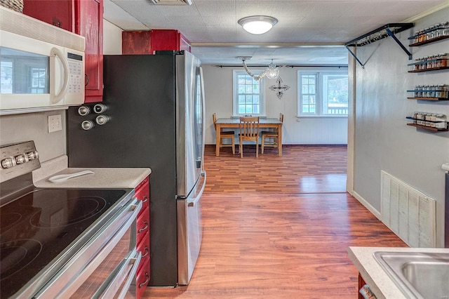 kitchen featuring hardwood / wood-style floors, an inviting chandelier, and stainless steel electric stove