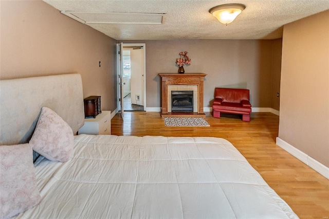 bedroom featuring hardwood / wood-style floors, a fireplace, and a textured ceiling