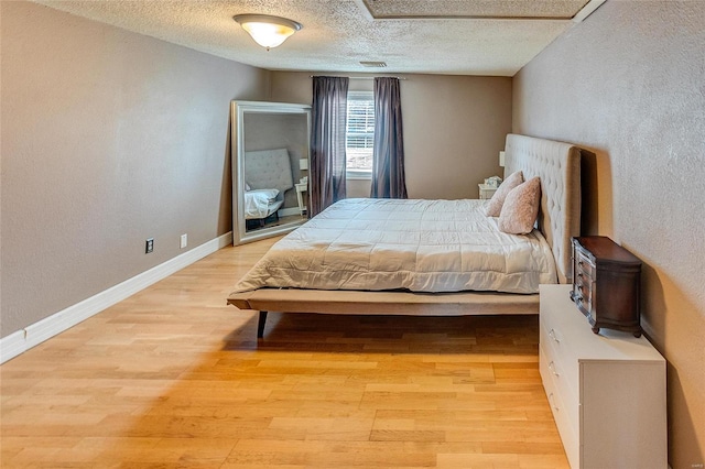 bedroom with light wood-type flooring and a textured ceiling