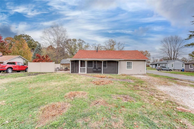 rear view of property featuring a sunroom and a lawn