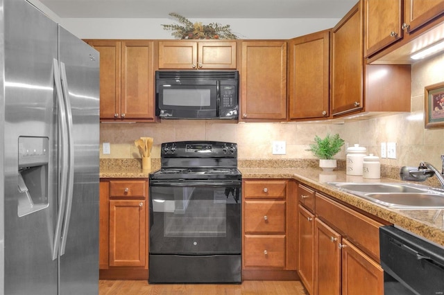 kitchen with decorative backsplash, sink, black appliances, and light hardwood / wood-style floors