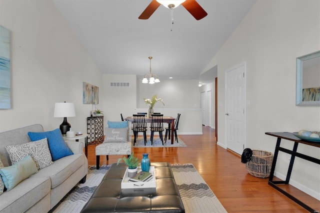 living room featuring hardwood / wood-style floors, ceiling fan with notable chandelier, and vaulted ceiling