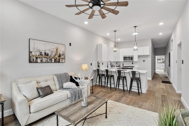 living room featuring ceiling fan, sink, and light hardwood / wood-style flooring