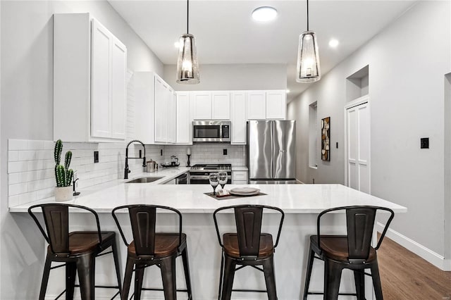 kitchen with stainless steel appliances, white cabinetry, sink, a kitchen breakfast bar, and dark wood-type flooring