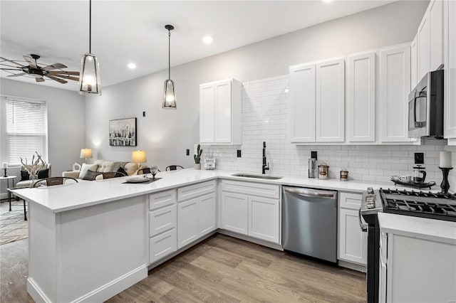 kitchen with white cabinets, appliances with stainless steel finishes, sink, and pendant lighting