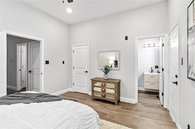 bedroom featuring ceiling fan, connected bathroom, sink, and light wood-type flooring