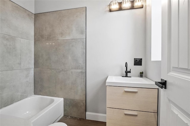 bathroom with toilet, hardwood / wood-style floors, vanity, and a tub