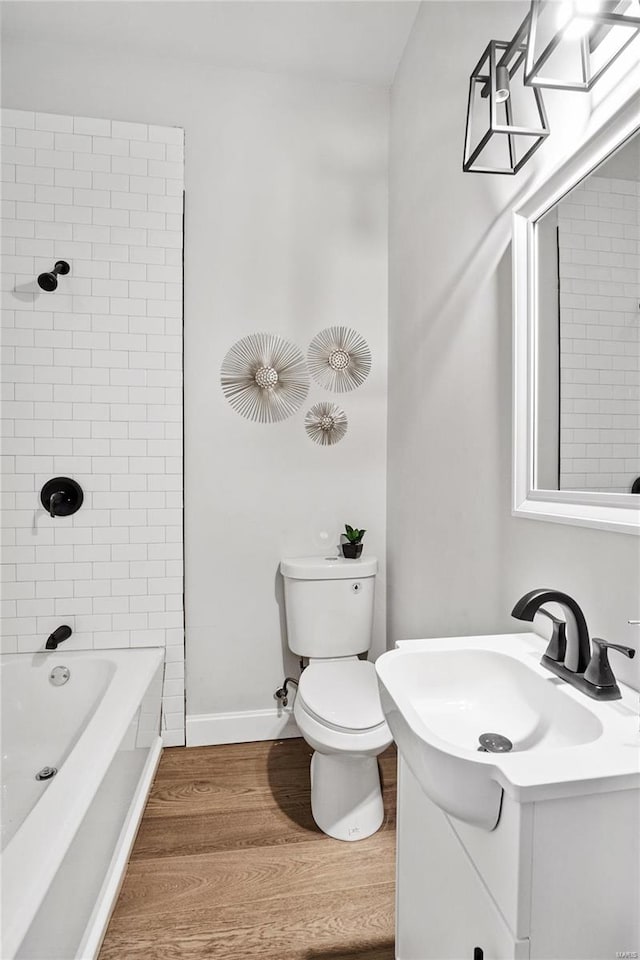 full bathroom featuring hardwood / wood-style flooring, vanity, toilet, and tiled shower / bath