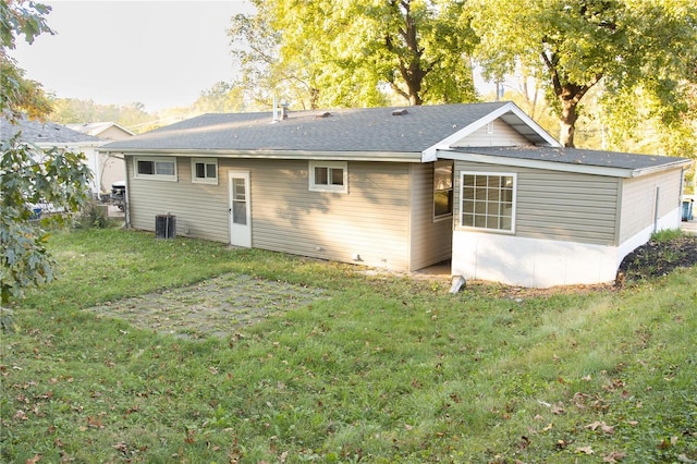 back of property with central air condition unit and a yard