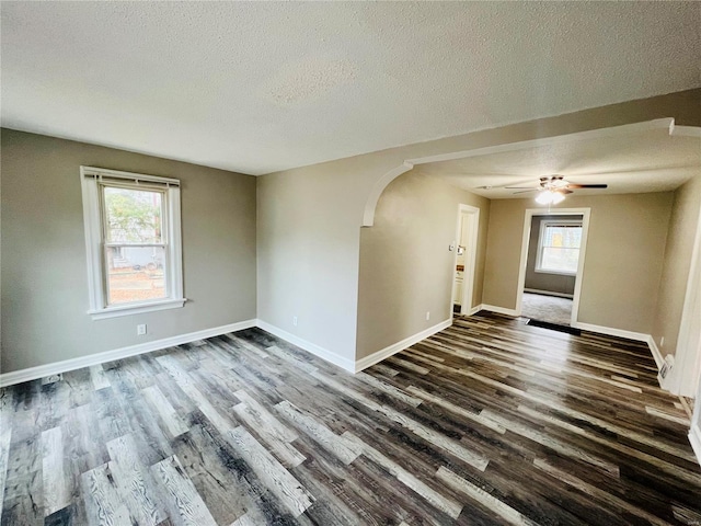 unfurnished room with dark wood-type flooring, a textured ceiling, and plenty of natural light