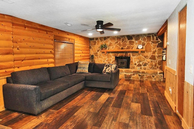 living room featuring a textured ceiling, a wood stove, dark hardwood / wood-style flooring, and rustic walls