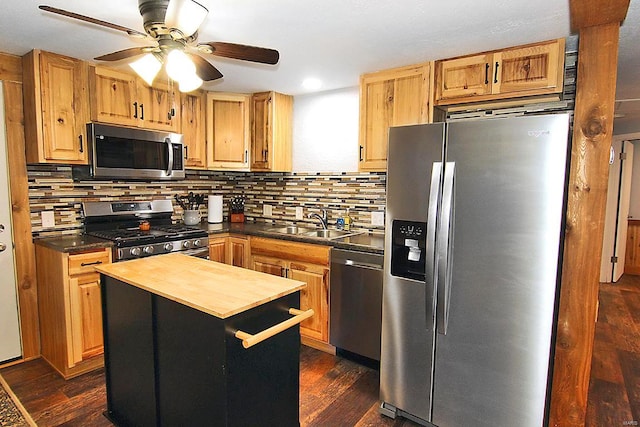 kitchen with butcher block countertops, appliances with stainless steel finishes, a center island, and dark hardwood / wood-style floors