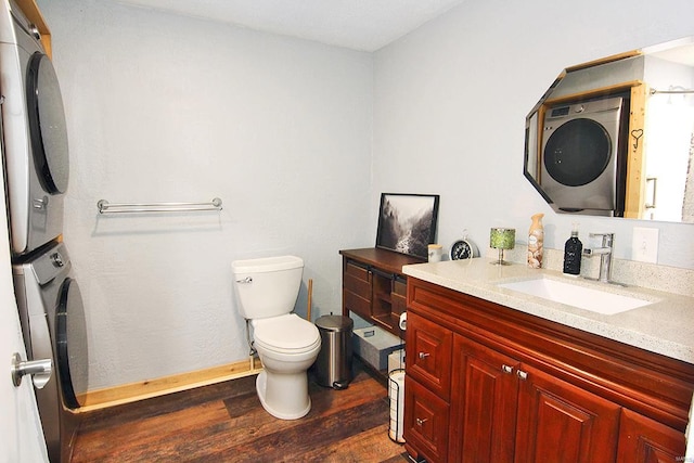 bathroom featuring toilet, stacked washer / drying machine, vanity, and wood-type flooring