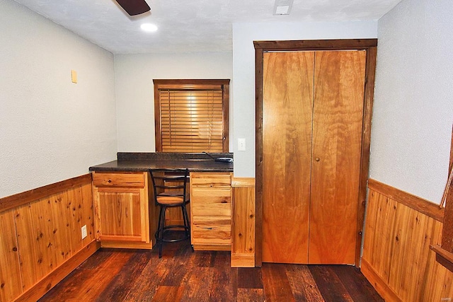 bar featuring dark hardwood / wood-style floors, wooden walls, and ceiling fan