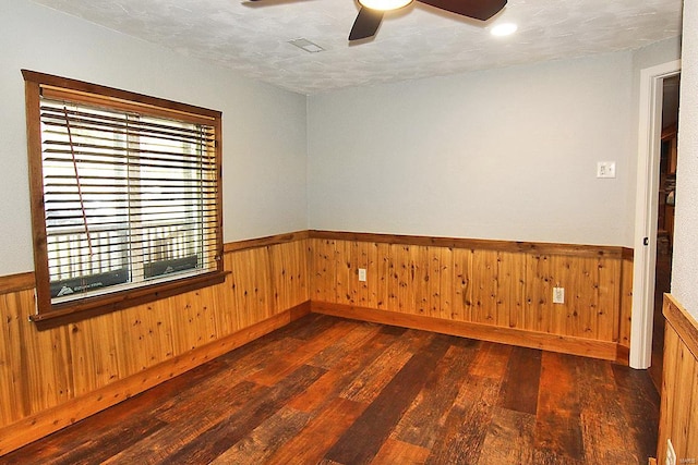 unfurnished room featuring a textured ceiling, wooden walls, and dark hardwood / wood-style floors