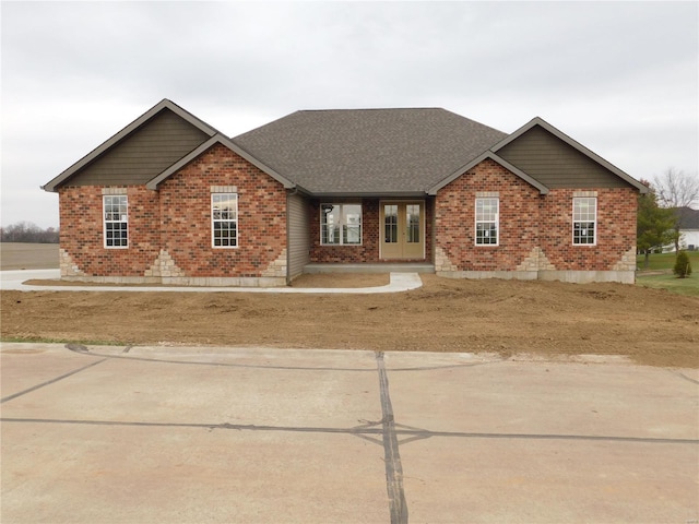 view of front of property with roof with shingles and brick siding