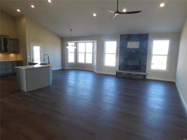 kitchen with dark wood-type flooring, plenty of natural light, a fireplace, and a center island with sink