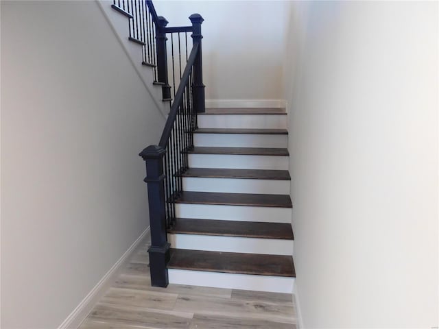 staircase featuring wood finished floors and baseboards