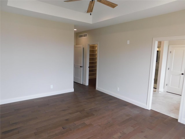 unfurnished room featuring ceiling fan, dark wood-type flooring, visible vents, and baseboards