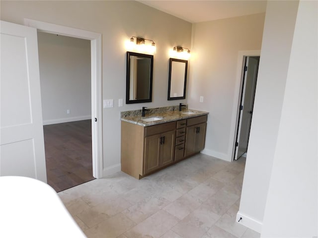 full bath with double vanity, baseboards, and a sink