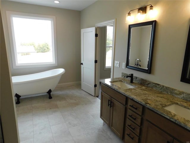 bathroom featuring plenty of natural light, a freestanding tub, and a sink