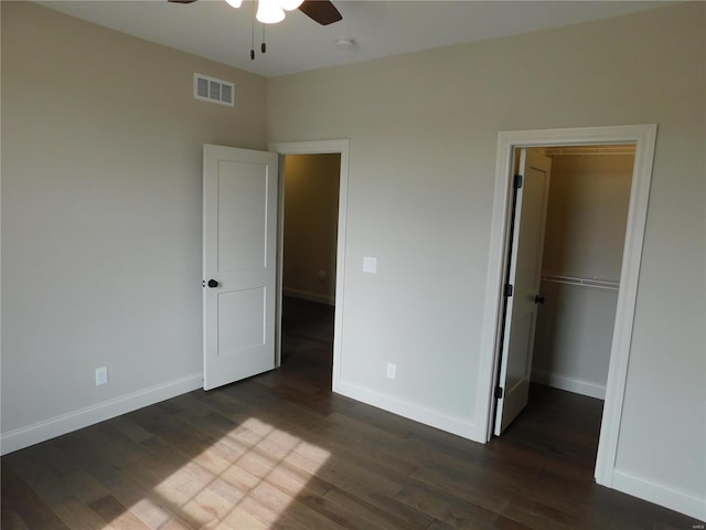 unfurnished bedroom with dark wood-type flooring, visible vents, and baseboards