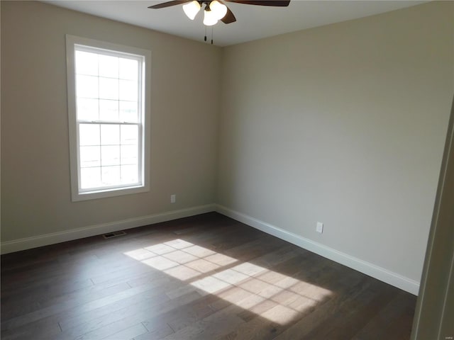 spare room featuring dark wood-type flooring, visible vents, ceiling fan, and baseboards