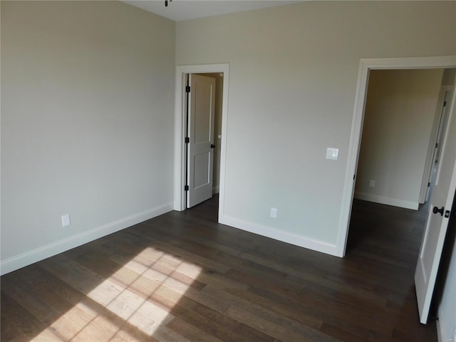 unfurnished bedroom with baseboards and dark wood-type flooring