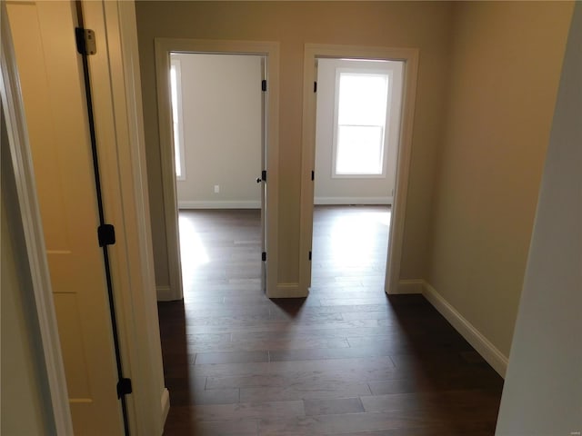 hallway with dark wood-style flooring and baseboards