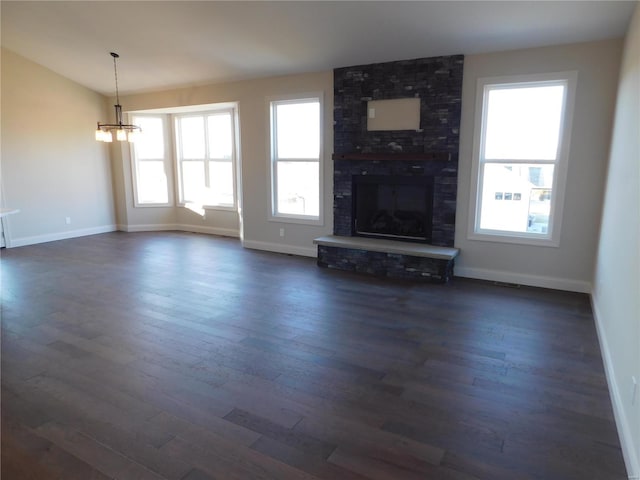 unfurnished living room with dark wood-style floors, a brick fireplace, a chandelier, and baseboards