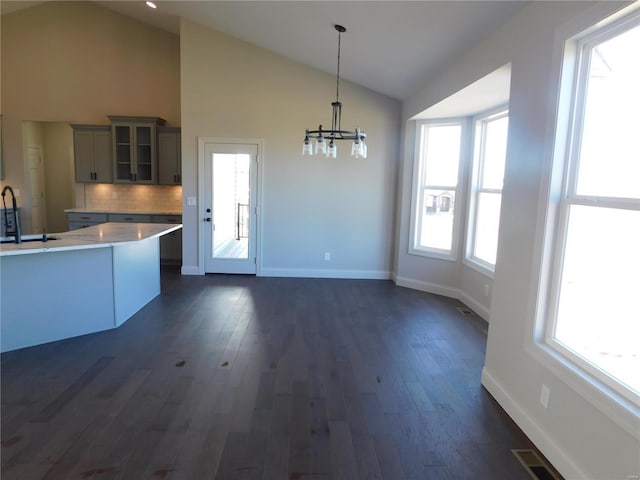 kitchen with dark wood-style flooring, glass insert cabinets, a sink, and decorative light fixtures