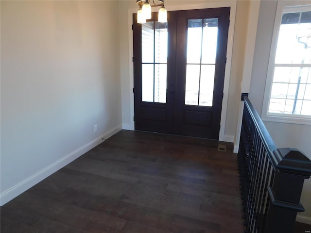 doorway to outside with french doors, a notable chandelier, dark wood finished floors, and baseboards