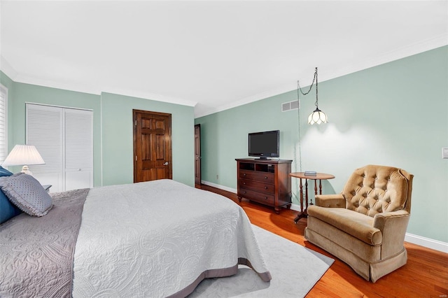 bedroom with crown molding, hardwood / wood-style floors, and a closet