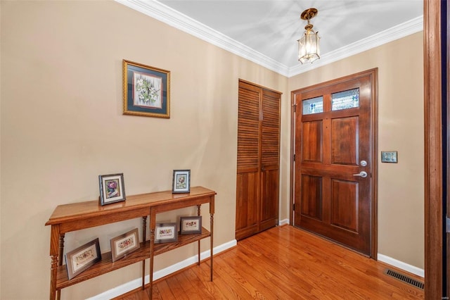 foyer featuring an inviting chandelier, ornamental molding, and light hardwood / wood-style floors