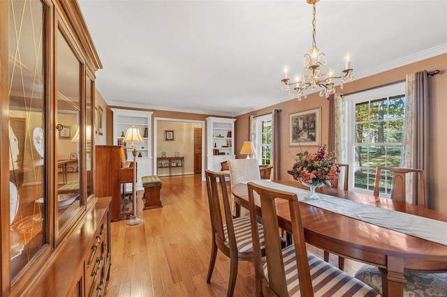 dining room with ornamental molding, a healthy amount of sunlight, an inviting chandelier, and light hardwood / wood-style flooring