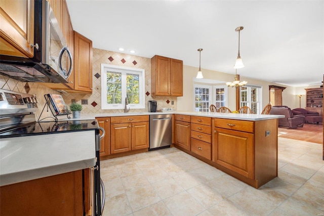 kitchen featuring sink, appliances with stainless steel finishes, hanging light fixtures, decorative backsplash, and kitchen peninsula