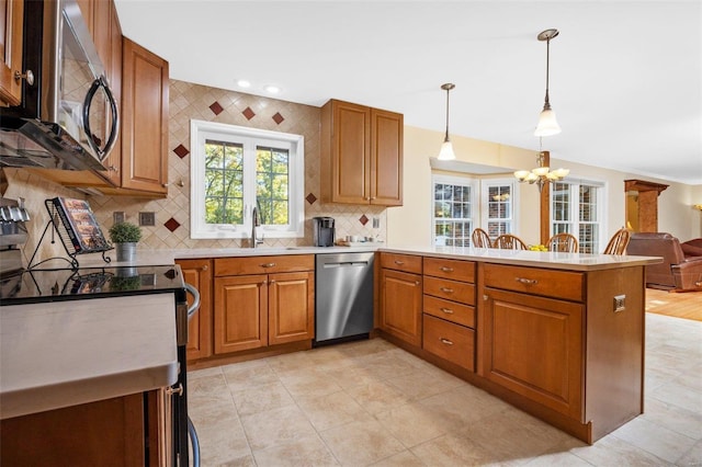 kitchen featuring pendant lighting, tasteful backsplash, sink, kitchen peninsula, and stainless steel appliances