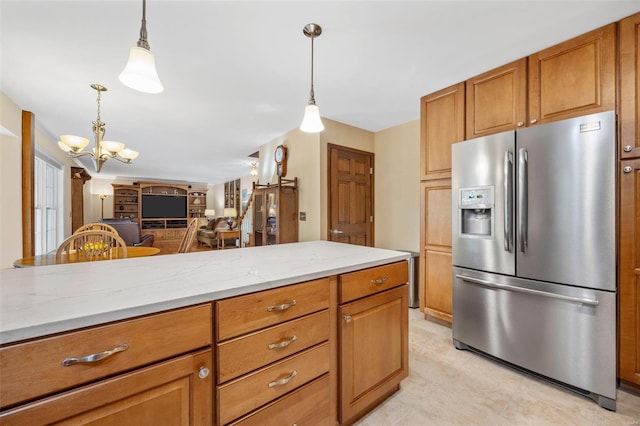 kitchen featuring pendant lighting, stainless steel fridge, and light stone counters