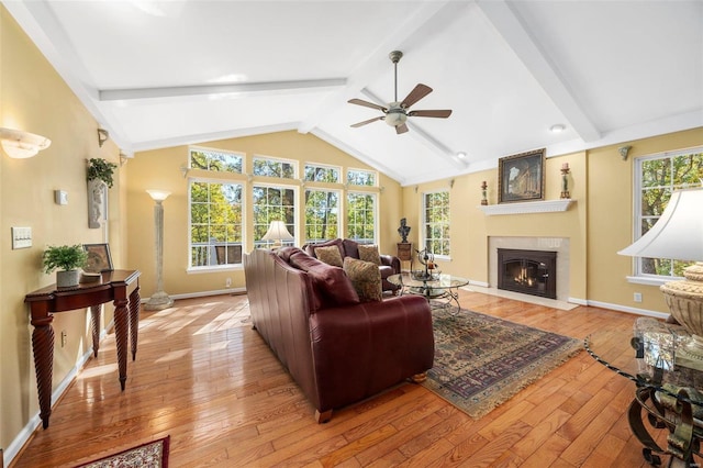 living room featuring ceiling fan, light hardwood / wood-style floors, and vaulted ceiling with beams