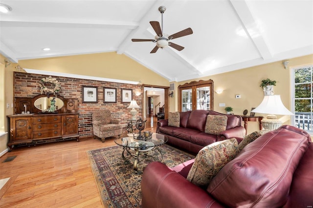 living room featuring ceiling fan, brick wall, vaulted ceiling with beams, and light wood-type flooring