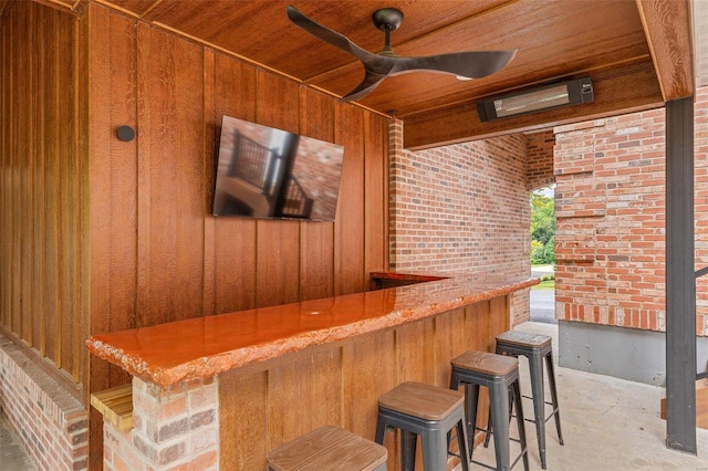 bar featuring wood ceiling, wood walls, and brick wall