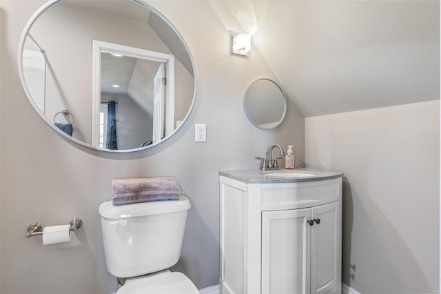 bathroom with vanity, toilet, and vaulted ceiling