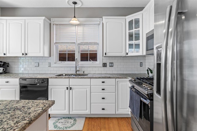 kitchen featuring hanging light fixtures, white cabinetry, sink, light hardwood / wood-style floors, and stainless steel appliances