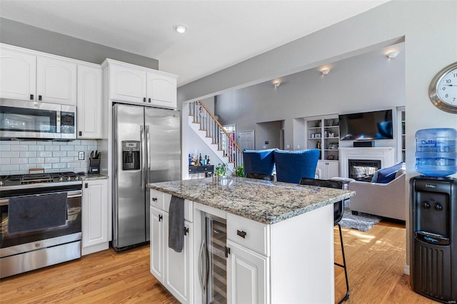 kitchen with a breakfast bar, white cabinets, light hardwood / wood-style flooring, and stainless steel appliances