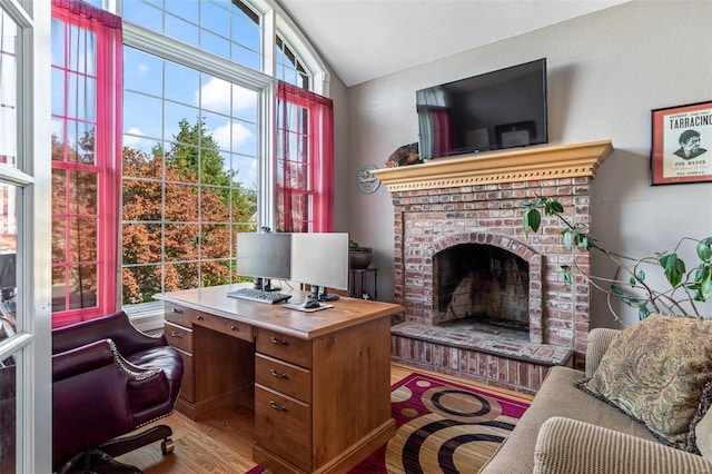 office space featuring hardwood / wood-style floors, vaulted ceiling, and a brick fireplace