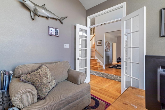 living area with french doors, wood-type flooring, and vaulted ceiling