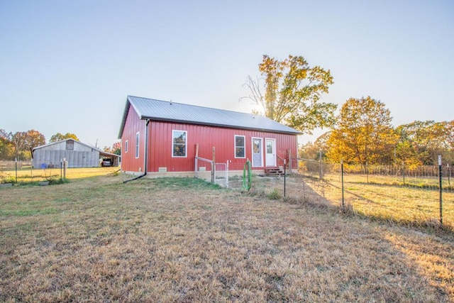 back of property with an outdoor structure and a yard