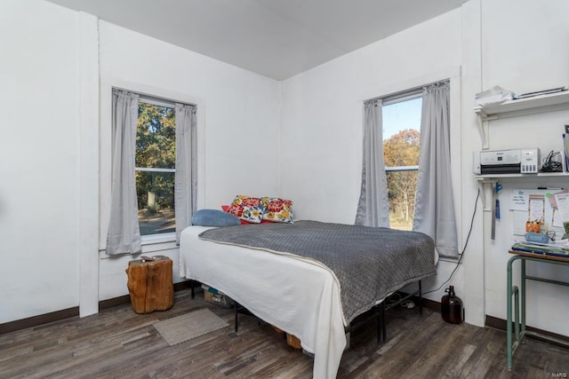 bedroom with multiple windows and dark wood-type flooring