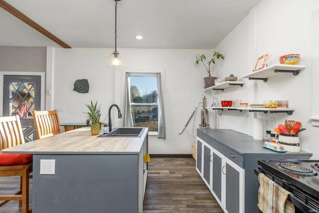 kitchen with gray cabinetry, sink, dark hardwood / wood-style flooring, decorative light fixtures, and a center island with sink