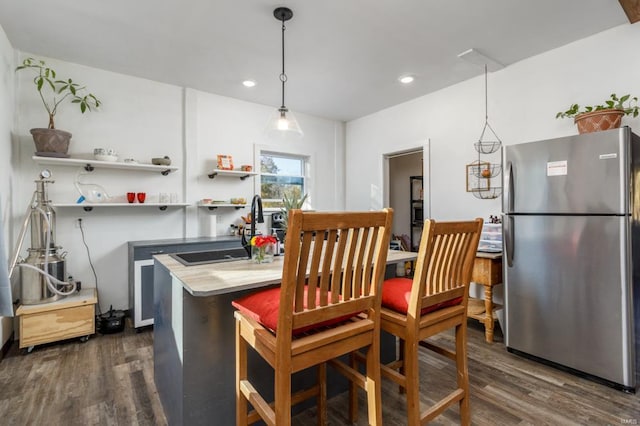 kitchen with stainless steel refrigerator, dark hardwood / wood-style flooring, decorative light fixtures, and sink